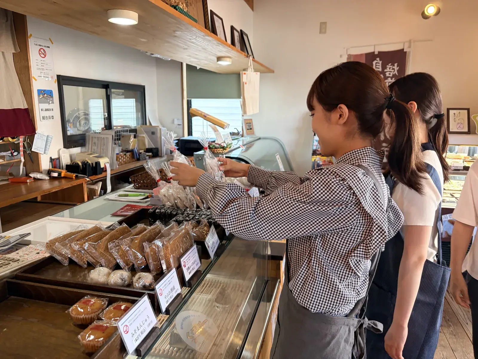 袋詰めした商品を店内に陳列する学生