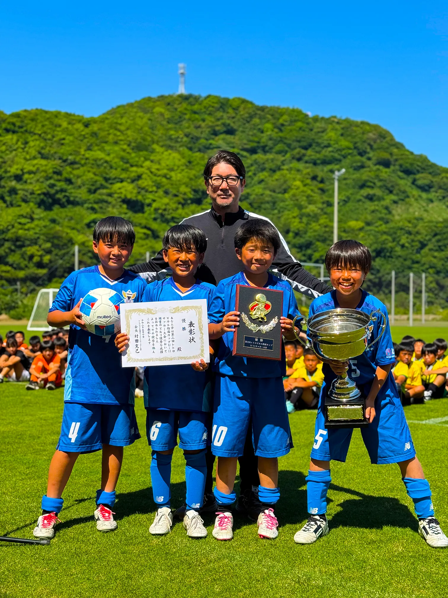 優勝したFCリベルタの代表選手4名とコーチが表彰状、優勝盾、トロフィーを持って記念撮影