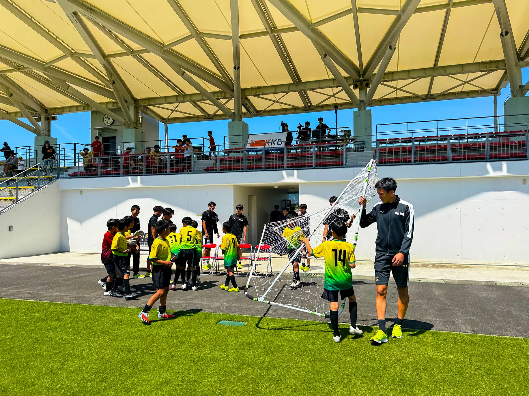 神村学園の選手と子どもたちが一緒にミニゴールを運んでいる様子