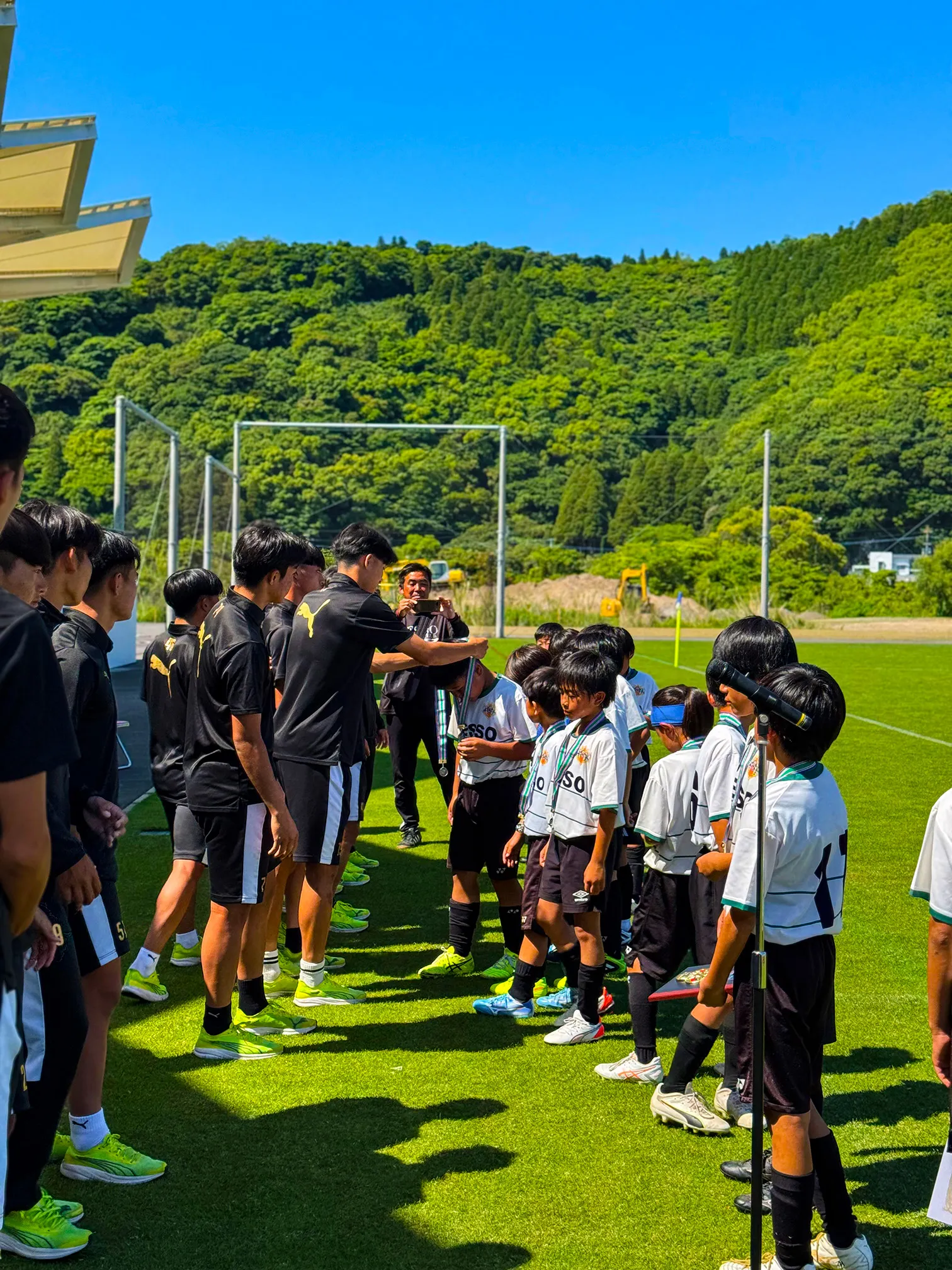 神村学園の選手が子どもたちの首にメダルをかけている表彰式の様子